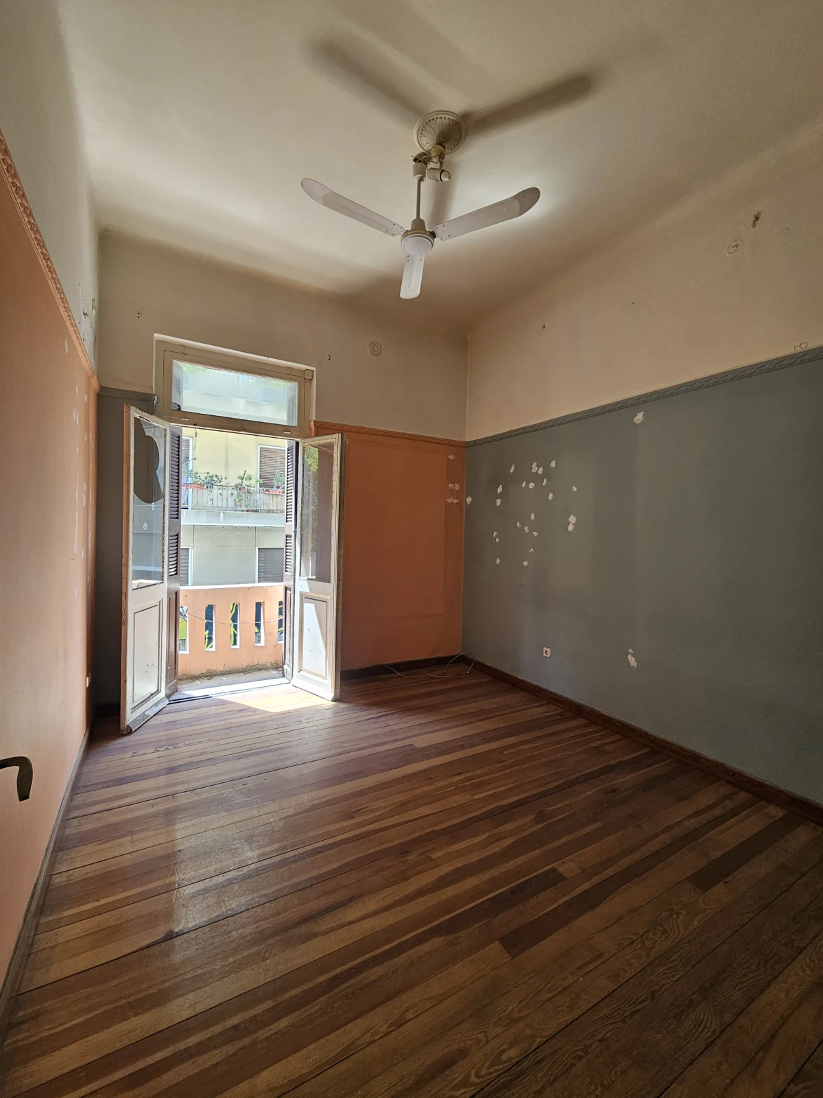 First floor, current condition — room with balcony doors and ceiling fan
